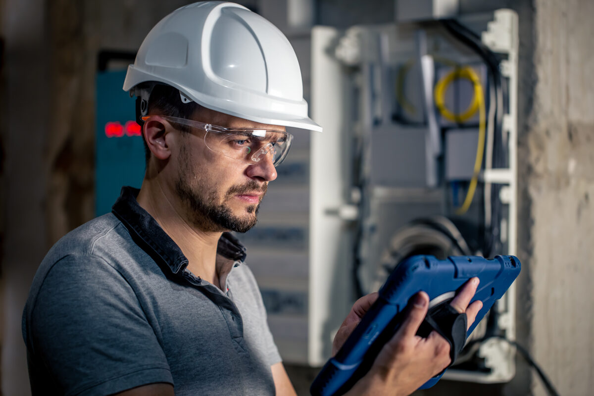 man-electrical-technician-working-switchboard-with-fuses-uses-tablet-1.jpg